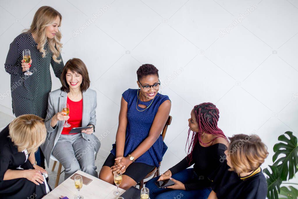 Portrait of female business team in modern studio with glasses of champagne.