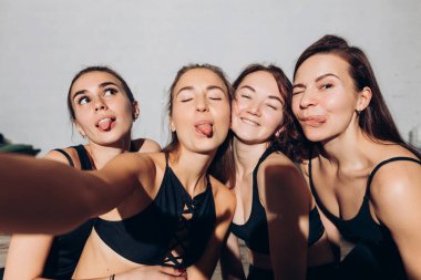 Çılgın genç kadınlar şık sporlar yapıyorlar. Kameraya dillerini gösteriyorlar.