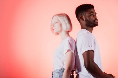 Albino kadın ve Afro adam sırt sırta dururlar.