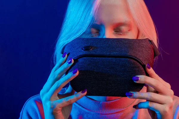 Ξανθό κορίτσι που κρατά γυαλιά VR, απομονωμένο μπλε φόντο — Φωτογραφία Αρχείου