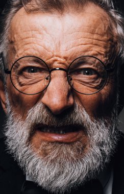 Yüzünde kızgın, şeytani korku ifadesi olan yaşlı adam, siyah arka plana yaklaş.