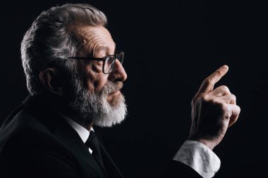 Gri saçlı bilim adamının resmi olarak siyah takım elbise giydiğini gösteren bir fotoğraf.