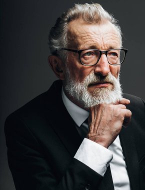 Yuvarlak gözlüklü, şık takım elbiseli, kameraya bakan olgun, akıllı bir adam.