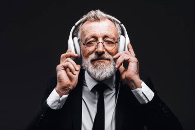 Gri saçlı, kulaklıklı iş adamı, müzik dinliyor, ruhu için dinleniyor..