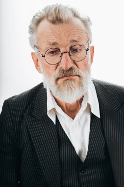 Resmi siyah takım elbiseli dalgın bir iş adamı, avuçlarını çenesinin yanında tutuyor.