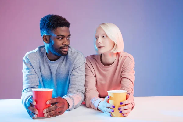 Multiracial young woman and a young man seating at a table — Stock Photo, Image