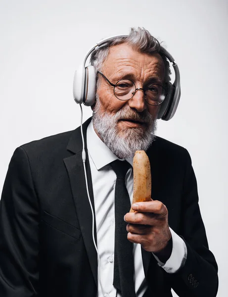 Volwassen zakenman die banaan eet en luistert naar audioboek met behulp van een koptelefoon. — Stockfoto