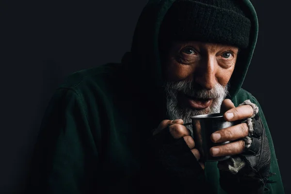 那个留着灰胡子的无家可归的老人拿着一大杯热茶取暖. — 图库照片
