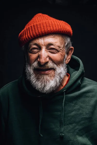 Feliz hombre optimista de 70 años con la cara arrugada sonriente, aislado en la oscuridad —  Fotos de Stock