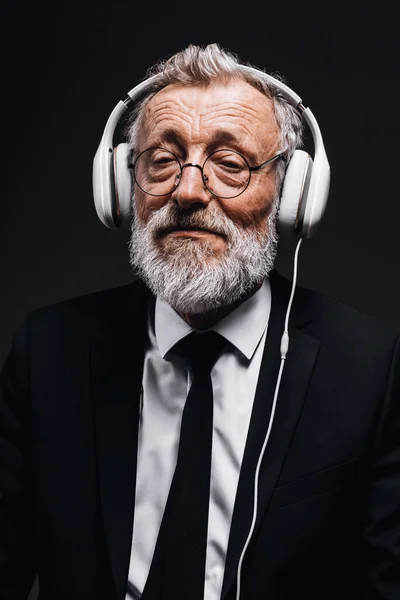 Oude chef-dirigent van symfonieorkest luisteren naar concert met behulp van koptelefoon — Stockfoto