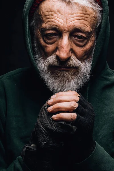 Obdachloser in grüner Altkleidung zittert vor Kälte, versucht sich aufzuwärmen. — Stockfoto