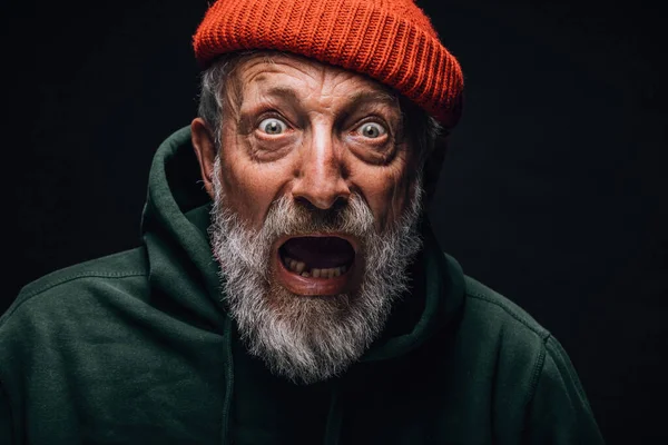 Scared shocked bearded old man stares at camera with open mouth, bugged eyes. — Stock Photo, Image