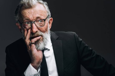 Yuvarlak gözlüklü, şık takım elbiseli, kameraya bakan olgun, akıllı bir adam.