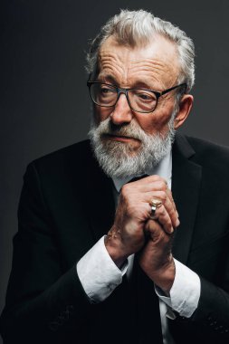 Yuvarlak gözlüklü, şık takım elbiseli, kameraya bakan olgun, akıllı bir adam.