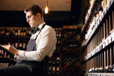 Sommelier, mahzendeki şarap ürünleri hakkında bilgi içeren notlar yazar.