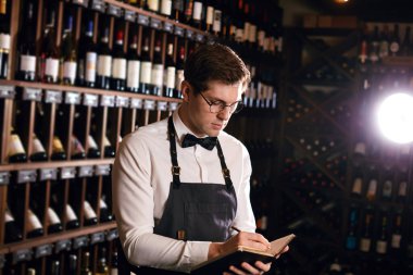 Sommelier, mahzendeki şarap ürünleri hakkında bilgi içeren notlar yazar.