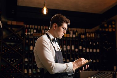 Sommelier, mahzendeki şarap ürünleri hakkında bilgi içeren notlar yazar.
