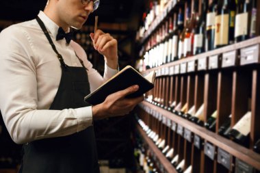 Sommelier şarap dükkanındaki şarap ürünleri hakkında bilgi yazıyor.