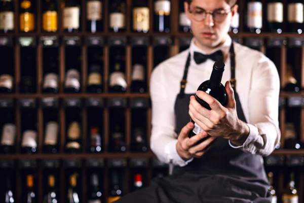 Кавказін елегантний самець-соммельєр з пляшкою вина біля стійки у винному магазині. — стокове фото