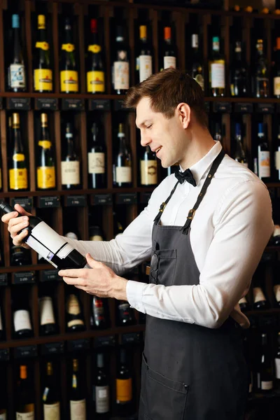 Koyu şarap evinin arka planında şarap şişesi olan barist ya da şarap satıcısı. — Stok fotoğraf