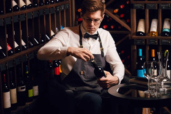 Бармен відкриває пляшку вина з пробкою в ресторані з винними полицями . — стокове фото