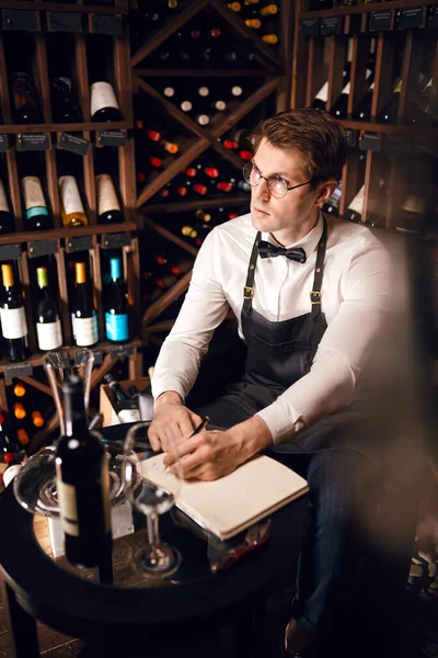 Sommelier, mahzendeki şarap ürünleri hakkında bilgi içeren notlar yazar. — Stok fotoğraf