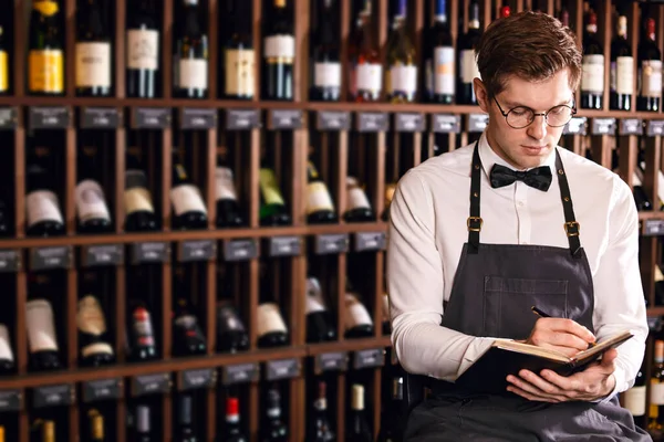 Sommelier writes a, putting down information on wine products in wine store