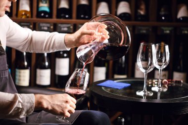 Şarap tadımcısı ya da degustatör kırmızı şarabı sürahiye doldurup mükemmel bir renk yaratıyor.