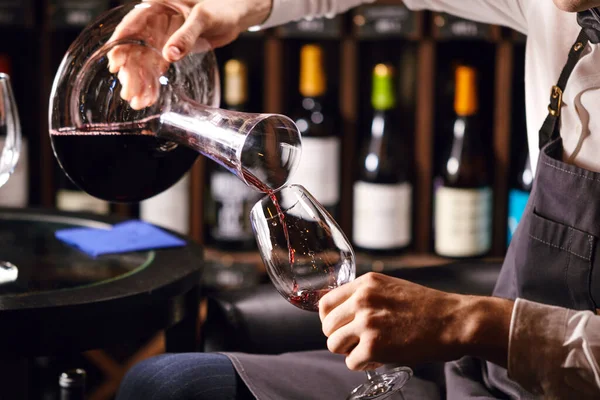 Skilled sommelier pouring wine from decanter ino wine glass. — Stock Photo, Image