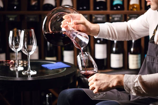 Sommelier ρίχνει κόκκινο κρασί από μπουκάλι σε καράφα στο τραπέζι στο εστιατόριο — Φωτογραφία Αρχείου