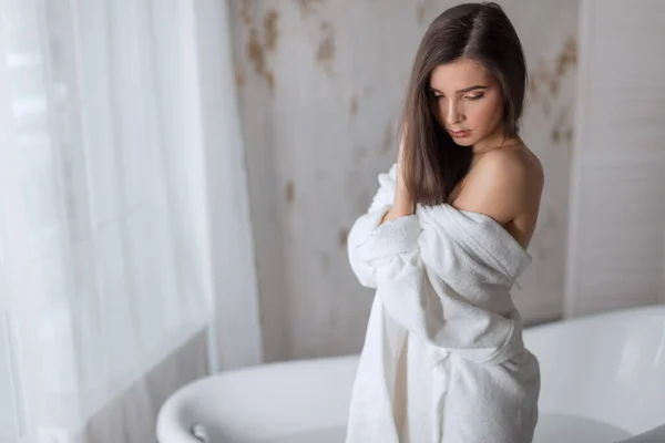 Mooi jong brunette vrouw poseren in een badjas — Stockfoto