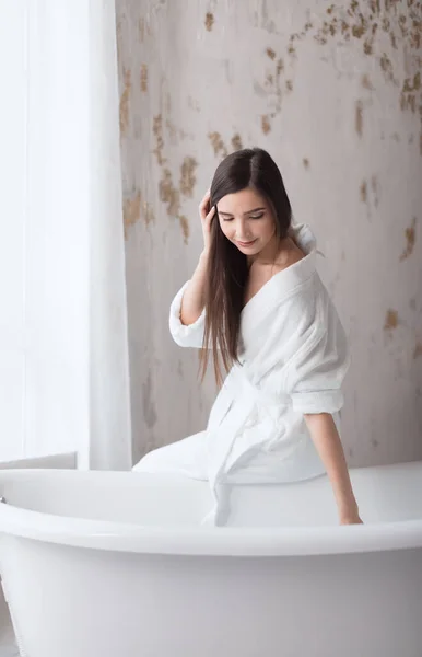 Spa chica europea en bata blanca, preparándose para el baño, mirando hacia el agua — Foto de Stock