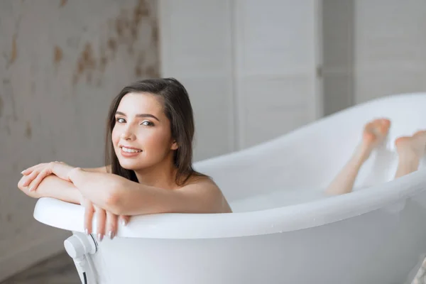 Mujer relajante en baño lleno de leche en el centro de spa —  Fotos de Stock