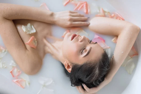 꽃잎으로 젖 냄새 목욕을 하는 젊은 여자 — 스톡 사진