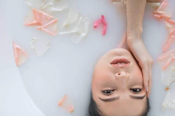 Gros plan du visage féminin relaxant dans l'eau laiteuse blanche, regardant la caméra — Photo