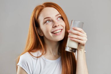 Doymuş bir kadın elinde bir bardak milkshake tutuyor ve hayal kuruyor.