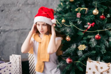 Çekici bir kız yerde otururken Noel şapkası takıyor.