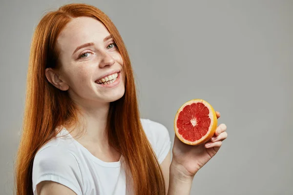 Sonriente chica sana mostrando una mitad de pomelo — Foto de Stock