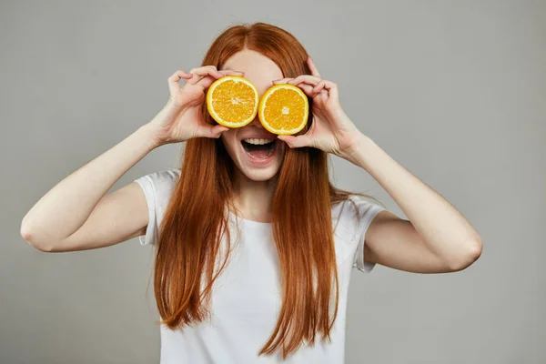 Sonriente vigilia cubriendo sus ojos con naranjas — Foto de Stock