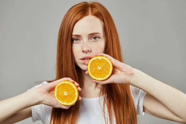 Chica con dos mitades de naranjas s sobre fondo gris — Foto de Stock