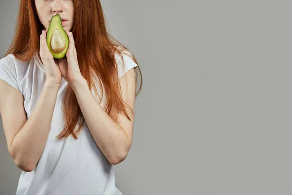 Cerca de foto recortada. chica posando con una mitad de aguacate —  Fotos de Stock