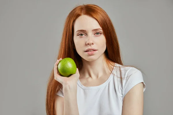 Urocza dziewczyna z zielonym jabłkiem patrząc w aparat — Zdjęcie stockowe