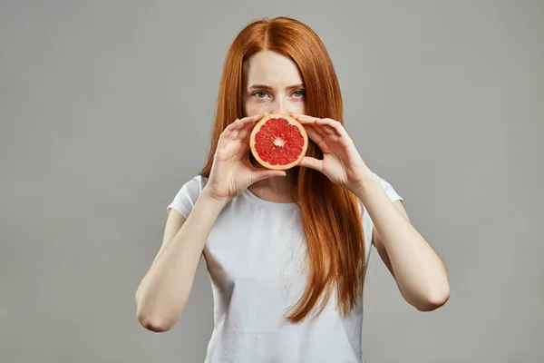 Hermosa chica cubriendo su boca con grepefruit — Foto de Stock