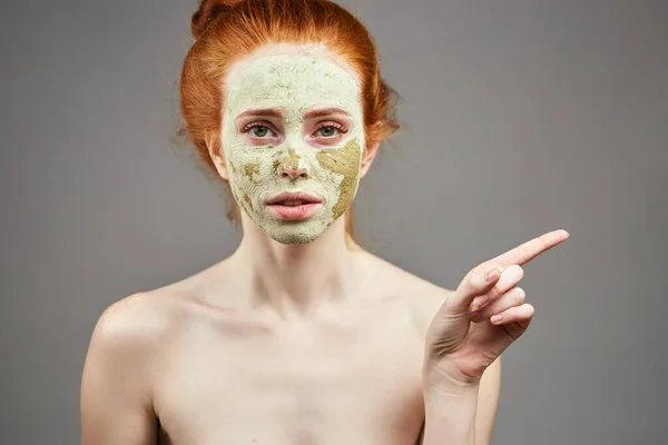 Agréable fille avec vert masque d'argile pointant quelque part — Photo