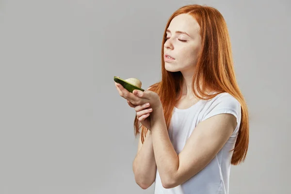 Foto da vicino vista laterale. bella ragazza sta tenendo un avocado su una palma — Foto Stock