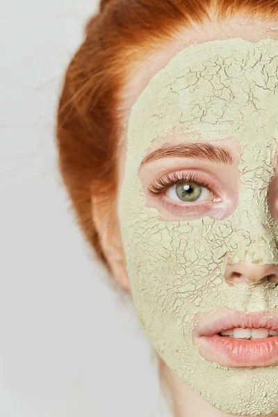 Impresionante chica de jengibre con máscara verde cosmética en la cara — Foto de Stock