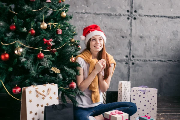 Trogen flicka sitter nära julgran och väntar på en magisk tid — Stockfoto