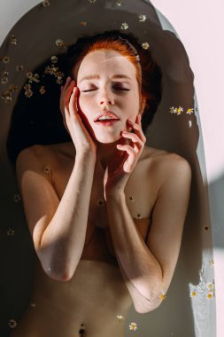 Güzel, baştan çıkarıcı, kızıl saçlı, küvette çıplak omuzlu bir bayan..