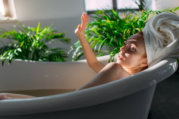 Рыжая женщина отдыхает в ванне с пеной в спа-центре.