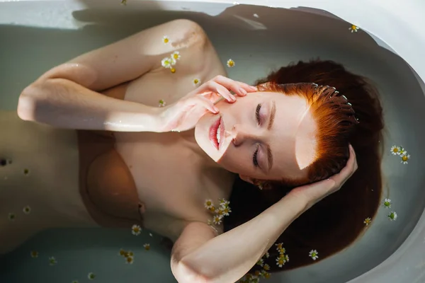Beautiful seductive young red-haired lady with bare shoulders in bathtub. — Stock Photo, Image